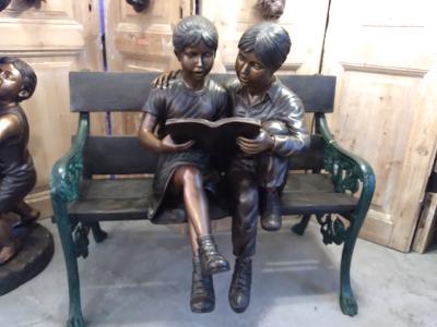 BOY AND GIRL WITH A BOOK ON A BENCH
